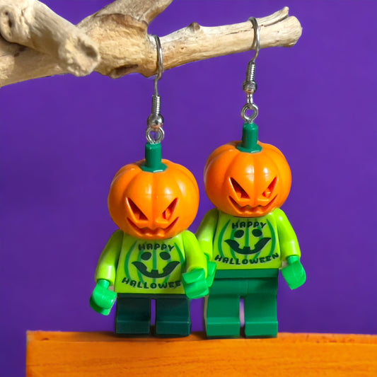 Two lego minfigures dressed in a green shirt with happy halloween on the shirt and green pants with a pumpkin head hanging on a branch with a purple background