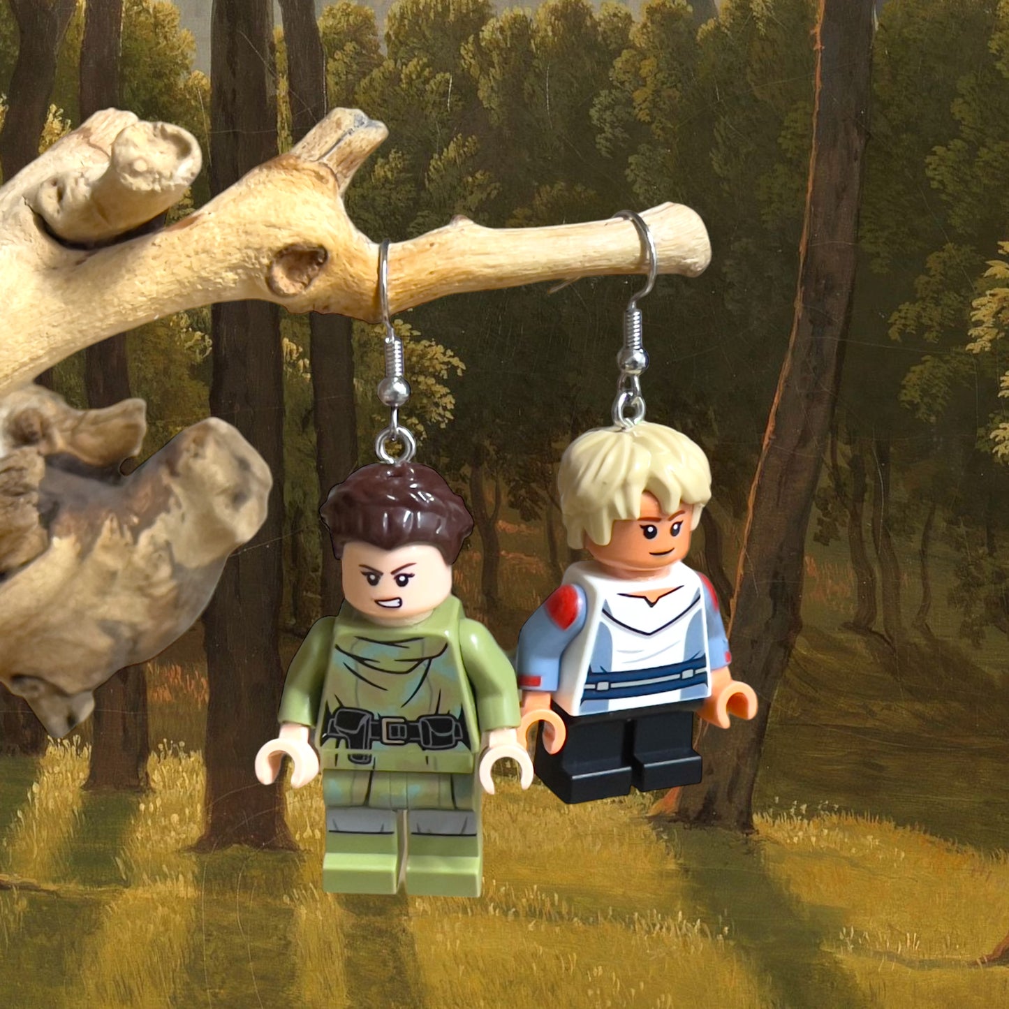 a lego minifigure of leia and Luke from star wars with Leia wearing a green outifit with a black utility belt and like wearing a blue and white shirt with red patches on his sleeves, with silver hook earrings hanging on a branch with a painted background of a green forest